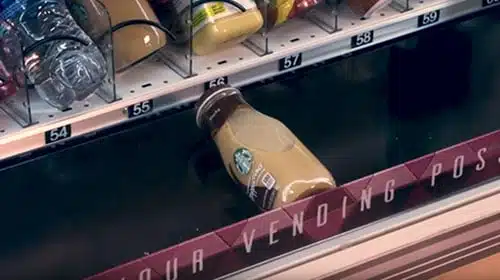 A photo of a glass drink bottle being safely lowered down by an elevator in one of our custom vending machines.